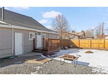 View of the backyard with a deck, small bbq table, and a partially snow-covered gravel area at 6521 E 70Th Pl, Commerce City, CO 80022