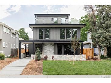 Stunning three-story home with a stone facade, modern wood siding, and rooftop terrace with glass railing at 1665 S Fillmore St, Denver, CO 80210