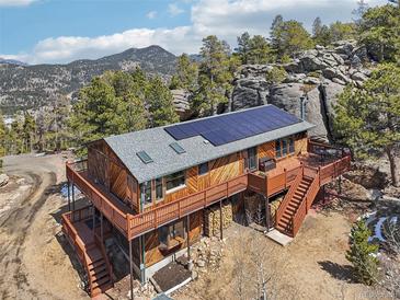 Stunning mountain home featuring a wraparound deck and solar panels, blending rustic charm with modern sustainability at 31911 Warrens Rd, Golden, CO 80403