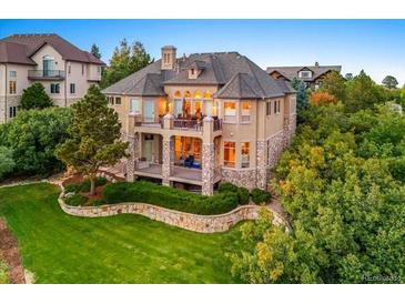 Spacious backyard featuring a large deck, stone accents, and lush landscaping at 1222 Buffalo Ridge Rd, Castle Pines, CO 80108