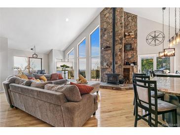 Bright living room with large windows, a stone fireplace, hardwood floors, and an open floor plan at 1758 Sinton Rd, Evergreen, CO 80439