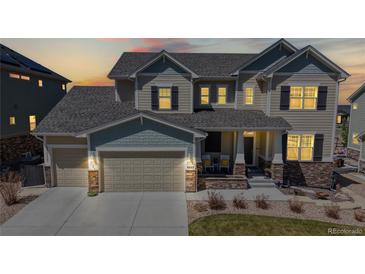 Beautiful two-story home with covered front porch during sunset with illuminated lighting at 8605 S Zante Ct, Aurora, CO 80016