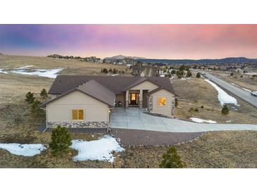 Stunning exterior view of a beige home with a brown roof, complemented by a long concrete driveway and scenic landscape at 20201 Royal Troon Dr, Monument, CO 80132