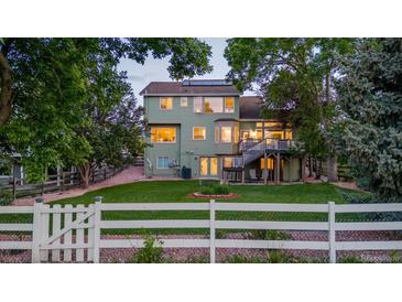 Spacious backyard with lush lawn, mature trees, large deck, and white picket fence at 6266 Holman St, Arvada, CO 80004