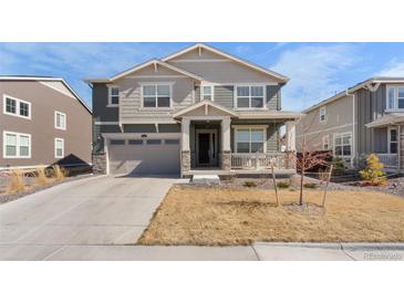 Two-story home featuring a covered front porch, a two-car garage, and neutral-tone siding at 14800 Hudson St, Thornton, CO 80602