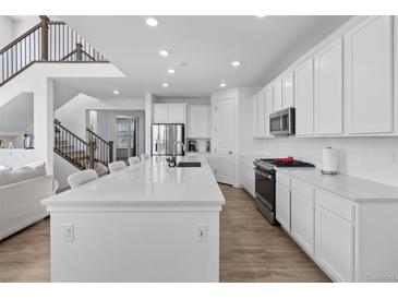 Bright kitchen boasts stainless appliances, white cabinets, and a large center island at 14800 Hudson St, Thornton, CO 80602