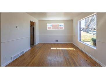 Bright living room with hardwood floors and lots of natural light from the large windows at 10454 Grant Dr, Northglenn, CO 80233