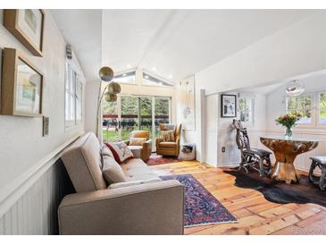 Bright living room with wood floors, modern furnishings, and large windows with exterior views at 27383 Highway 74, Evergreen, CO 80439