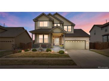 Two-story home featuring a well-maintained lawn, front porch, and a two-car garage with brick accents at 13475 Spruce St, Thornton, CO 80602