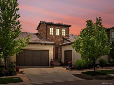 Charming stucco two-story home with a tiled roof, stone accents, mature landscaping, and a two-car garage at 15264 W La Salle Ave, Lakewood, CO 80228