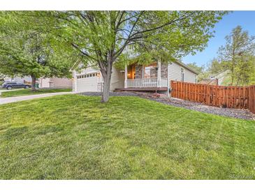 Charming home with a lush green lawn, a two-car garage and a quaint front porch at 16179 W 70Th Pl, Arvada, CO 80007