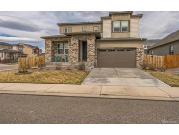 Inviting two-story home with a stone facade, a two-car garage, and a cozy front porch, perfect for relaxing at 13329 Newport Cir, Thornton, CO 80602