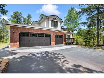 A beautiful home with a brick two-car garage and paved driveway surrounded by mature trees at 1240 Lone Scout Lookout, Monument, CO 80132