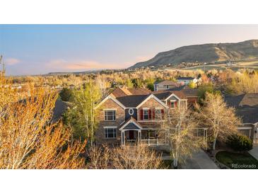 Beautiful sunset aerial view of the home featuring mature trees, and mountain views at 17294 W 60Th Ct, Arvada, CO 80403