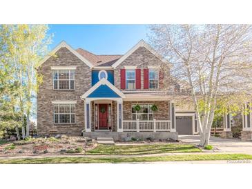 Charming two-story home featuring a lovely front porch, brick facade, and colorful details at 17294 W 60Th Ct, Arvada, CO 80403