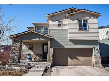 Inviting two-story home featuring a covered porch with stone accents and a two car garage at 162 Starlight Cir, Erie, CO 80516