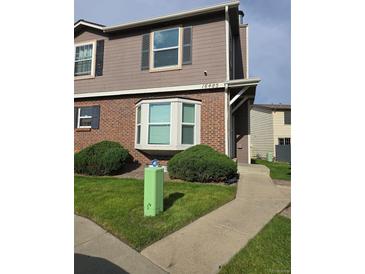 Charming townhome with a brick facade, bay window, and well-manicured landscaping in a residential neighborhood at 16485 E 17Th Pl # D, Aurora, CO 80011