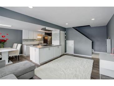 Open concept living room and kitchen with wood floors and a white shag rug at 1204 S Uvalda St, Aurora, CO 80012