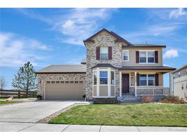 Charming two-story home with stone and tan siding, landscaped yard, and inviting front porch at 22268 E Hidden Trail Dr, Parker, CO 80138