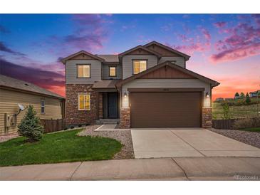 Two-story home featuring stone accents and a large garage, set against a vibrant sunset sky at 1018 Mcmurdo Cir, Castle Rock, CO 80108