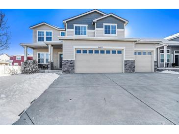 Charming two-story home with a three car garage and covered porch on a sunny day in winter at 5482 Wetlands Dr, Frederick, CO 80504