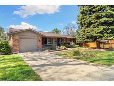 Charming brick home with a well-maintained front yard and a long driveway leading to the garage at 10868 W 70Th Ave, Arvada, CO 80004