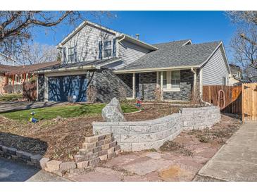 Two-story house with gray siding, stone accents, and a blue garage door at 11759 E Asbury Ave, Aurora, CO 80014