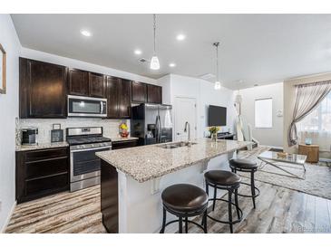 Open-concept kitchen featuring granite counters, stainless appliances, and a breakfast bar with seating at 15550 W 64Th Pl # D, Arvada, CO 80007