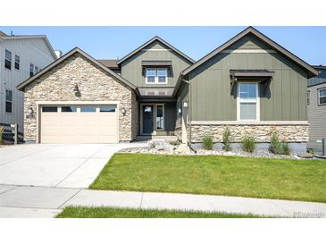 Beautiful exterior home with a stone accents, manicured lawn, and a convenient two-car garage at 6955 Sunstrand Ct, Castle Pines, CO 80108