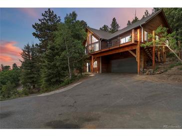 Two-story wood home with a drive-under garage, large windows, and a wrap-around balcony at 11760 Baca Rd, Conifer, CO 80433