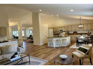 Bright and open-concept living space featuring hardwood floors, a kitchen island, and comfortable seating at 5554 S Ward Way, Littleton, CO 80127