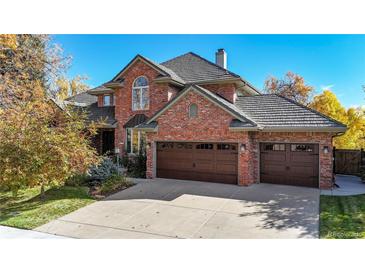Charming brick home featuring an attached three-car garage and lush landscaping at 10346 E Crestridge Ln, Englewood, CO 80111
