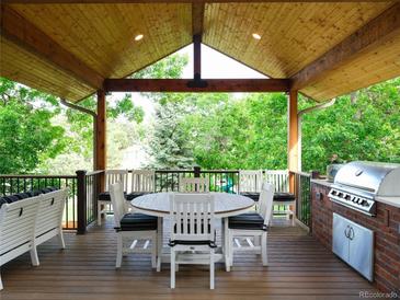 Covered outdoor kitchen featuring a built-in grill and dining area, perfect for entertaining at 10346 E Crestridge Ln, Englewood, CO 80111