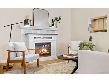 Cozy living room with a fireplace, two modern armchairs, and stylish décor at 7865 E Mississippi Ave # 105, Denver, CO 80247