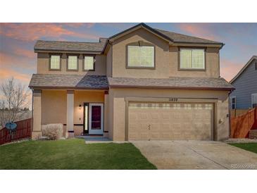 Two-story stucco home with a brown roof, attached garage, and green lawn at 11020 Glacier Park Cir, Parker, CO 80138