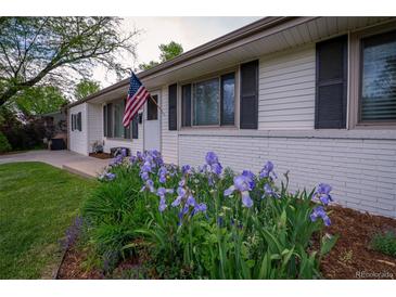 Charming home exterior with a well-maintained lawn and a garden with purple flowers in the front yard at 4425 E Harvard Ave, Denver, CO 80222