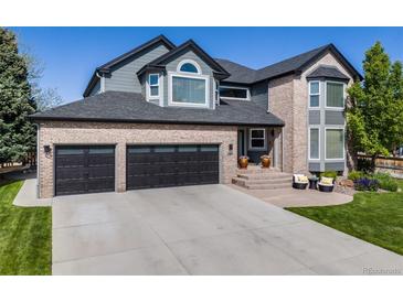 Beautiful home featuring a brick facade, black garage doors and inviting front porch with seating at 7067 Gray Fox Ct, Highlands Ranch, CO 80130