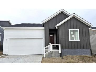 Charming home featuring a two-car garage, wooden siding, and inviting entryway at 17105 W 92Nd Loop, Arvada, CO 80007