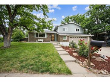 Charming two-story home featuring lush green lawn and landscaped front yard at 8935 W Swarthmore Dr, Littleton, CO 80123