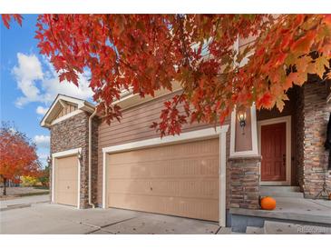 Spacious three car garage with stone accents, next to the covered front porch and red front door at 15003 W 63Rd Ave, Arvada, CO 80403