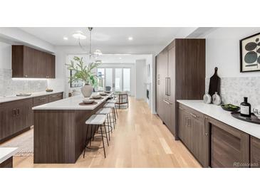 Modern kitchen with an expansive island, dark wood cabinets, light countertops and stainless steel appliances at 556 Monroe St, Denver, CO 80206