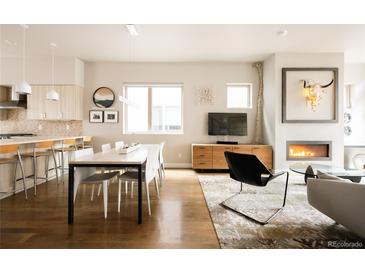 Open-concept living and dining area with hardwood floors and modern fireplace, perfect for entertaining and Gathering gatherings at 1012 Bannock St, Denver, CO 80204