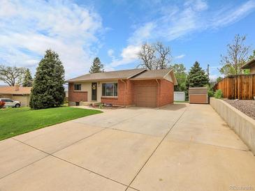 Charming brick and siding home featuring a well-maintained lawn, wide driveway and mature trees under a bright sky at 2797 S Newton Way, Denver, CO 80236
