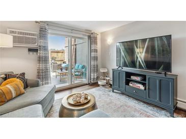 Bright living room with a sliding glass door to a private patio, and a modern entertainment center at 2835 S Monaco Pkwy # 1-103, Denver, CO 80222