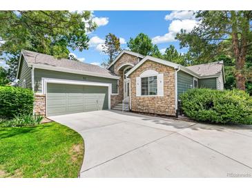 Charming home featuring stone accents, a well-manicured lawn, and an attached two-car garage at 7400 W Grant Ranch Blvd # 52, Littleton, CO 80123