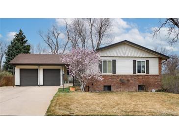 Charming home featuring a two-car garage, brick accents, and blossoming tree in the front yard at 6847 S Hill St, Littleton, CO 80120