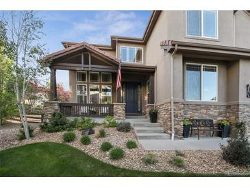 Inviting front porch with stone accents, dark wood, and manicured landscaping at 17490 W 67Th Ave, Arvada, CO 80007