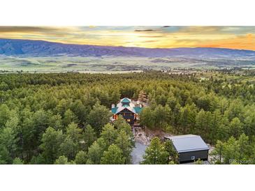 Expansive aerial view of a secluded home surrounded by lush forest and rolling hills at sunset at 5090 S Perry Park, Sedalia, CO 80135