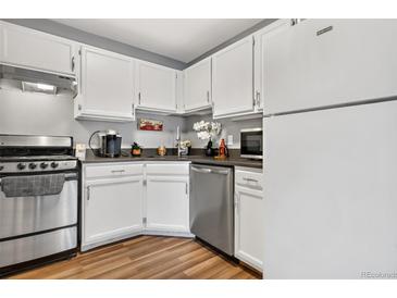 Well-lit kitchen featuring stainless steel appliances, white cabinetry, and wood-look flooring at 63 S Sable Blvd # 16, Aurora, CO 80012