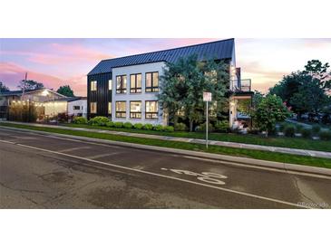 Modern home with white brick, black trim, a black metal roof and lush landscaping along a city street at 4590 Wolff St, Denver, CO 80212